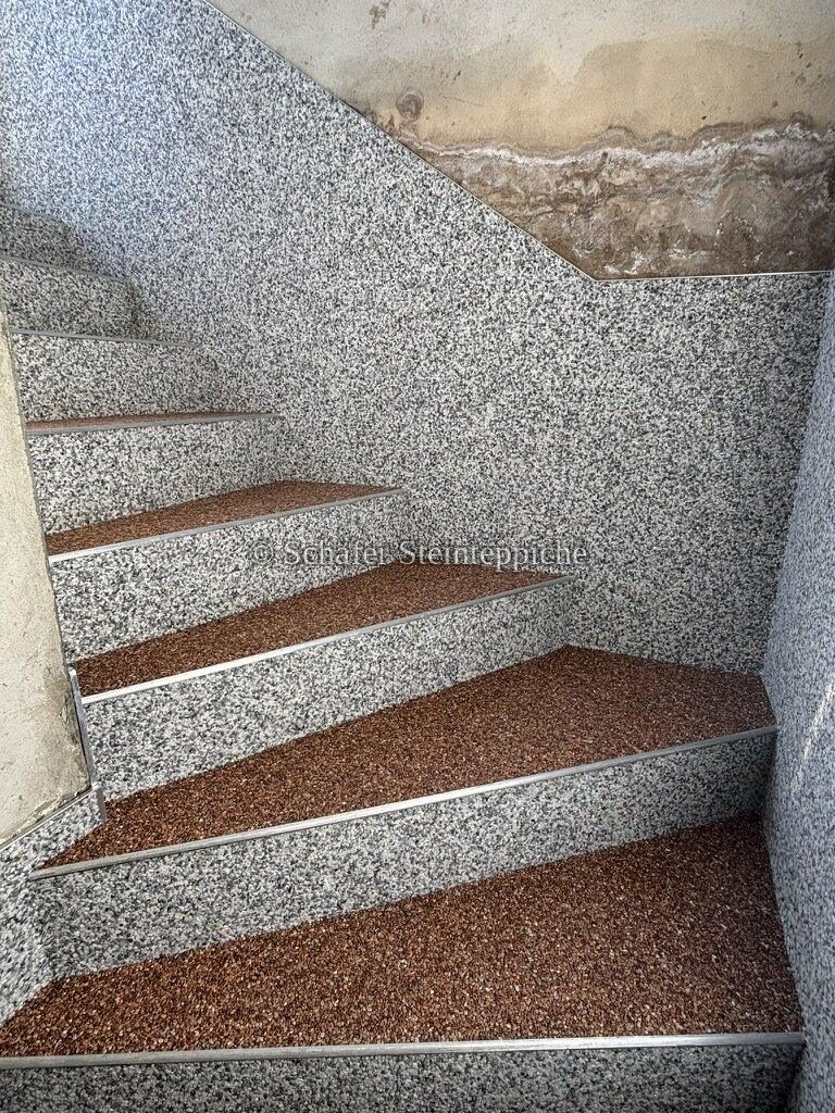 Treppenhaus mit fertigem Steinteppich, im Hintergrund unverputzte Wand